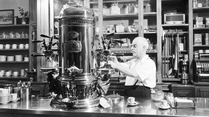 Máquina espresso histórica de gran formato utilizada en una cafetería, antecedente de las actuales máquinas de café a presión