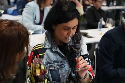 Una mujer con una original chaqueta vaquera de estilo pop-art huele una copa de vino tinto durante showcooking de Ourense en el Salón Gourmets