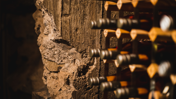 Botellas de vino almacenadas en una antigua cueva-bodega subterránea de piedra en Tarancón, símbolo del patrimonio vitivinícola de Castilla-La Mancha.