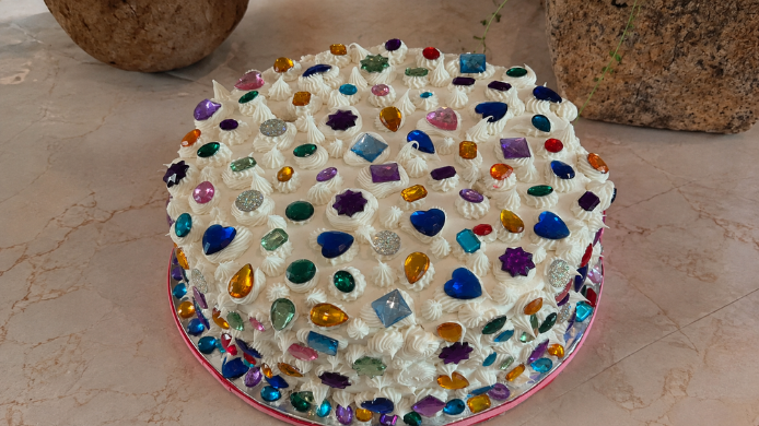 Tarta blanca decorada con gemas de colores, ejemplo de la tendencia bedazzling aplicada a la repostería.