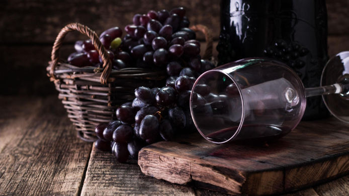 cesto con uvas y copa de vino tumbada