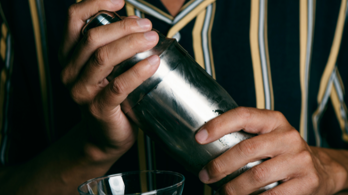 Bartender utilizando una coctelera metálica durante la preparación de un cóctel