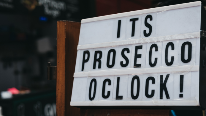 Cartel luminoso con el mensaje “It’s Prosecco o’clock” en la entrada de un establecimiento, como celebración del popular espumoso italiano.