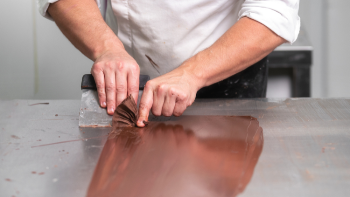Estudiantes trabajando bombones y cacao en una escuela profesional de chocolatería.