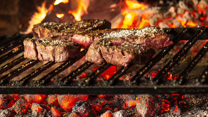 Chuletón a la brasa servido en un asador clásico con parrilla de fuego y ambiente tradicional de restaurante en Madrid