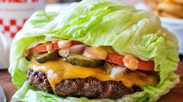 Hamburguesa sin pan envuelta en hojas de lechuga iceberg con carne, queso, tomate, pepinillos y salsa