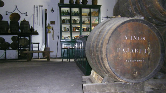 Interior de una bodega tradicional vinculada al vino pajarete, con barricas antiguas y una cuba rotulada, imagen representativa de la historia de este vino dulce andaluz.