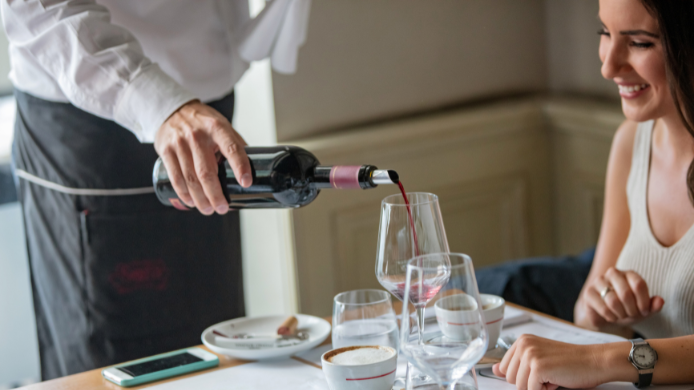 Camarero sirviendo vino a un comensal