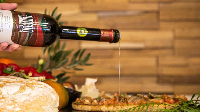 Aceite de oliva virgen extra ecológico Rincón de la Subbética cayendo sobre bruschetta artesanal en una presentación gourmet, almazaras de la subbética