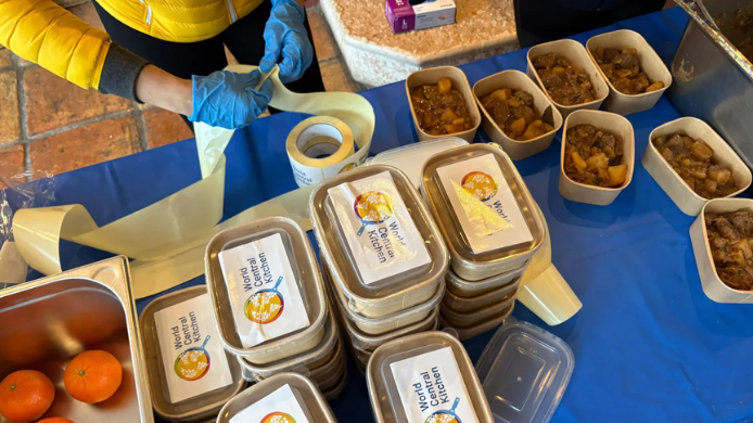 Voluntarios de World Central Kitchen preparan y etiquetan raciones de comida para personas afectadas por los incendios de Madrid y Ávila.