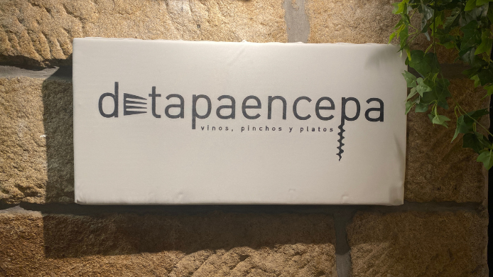 Cartel exterior de Detapaencepa sobre una pared de piedra, con el nombre del restaurante y el lema “vinos, pinchos y platos”.