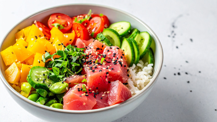 oke bowl de atún con arroz, mango, pepino, tomates cherry y edamame, espolvoreado con semillas de sésamo