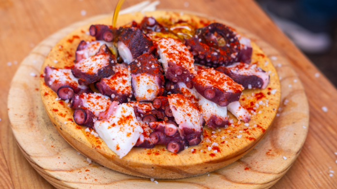 Pulpo á feira servido sobre plato de madera con aceite de oliva virgen extra, pimentón y sal gruesa, una de las recetas más emblemáticas de la gastronomía gallega.