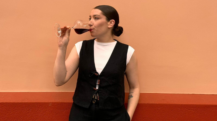 Isabel Ayala, sumiller de Tripea en Madrid, degustando una copa de Rosso di Valtellina frente a una pared de tonos cálidos