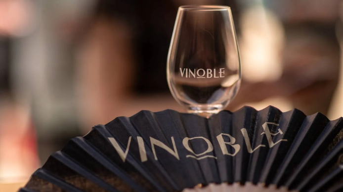 Copa serigrafiada de Vinoble junto a un abanico promocional del salón, imagen representativa del evento internacional dedicado a los vinos nobles celebrado en Jerez.