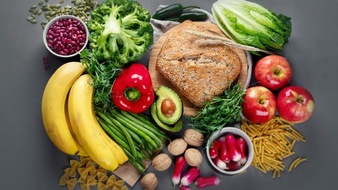 Selección de alimentos frescos y saludables compuesta por frutas, verduras, legumbres, frutos secos, aguacate, pan integral y pasta, representando una alimentación equilibrada basada en productos naturales y de origen sostenible.