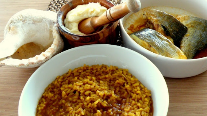 Arroz de caldero servido en plato con alioli y pescado