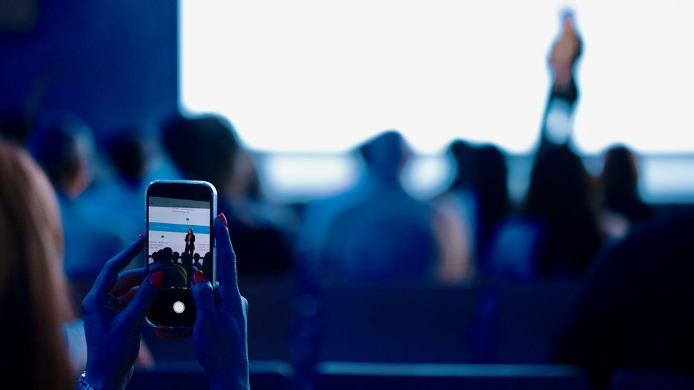 Asistente fotografiando una ponencia durante un congreso profesional, una imagen que refleja la transformación de los eventos gastronómicos en la era digital y el debate sobre su capacidad para seguir generando valor real.