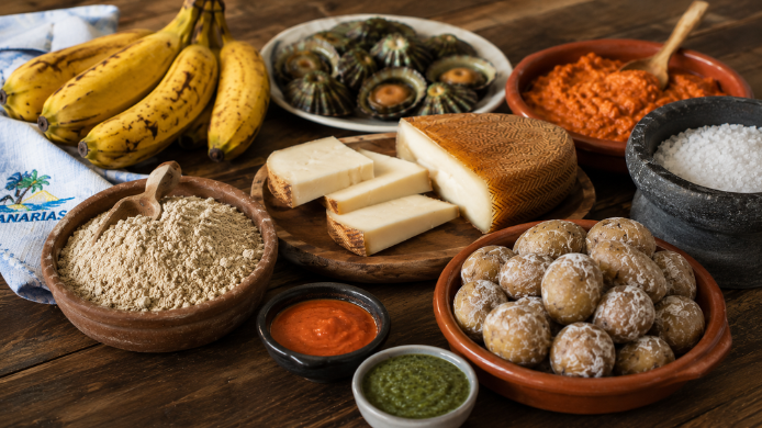 Mesa con productos tradicionales de la gastronomía canaria como gofio, papas arrugadas, mojo, queso majorero, plátanos y sal marina