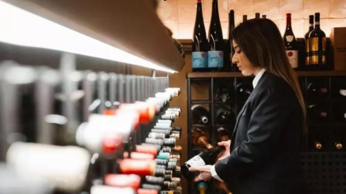 Rebeca seleccionando una botella entre las referencias de una bodega climatizada.
