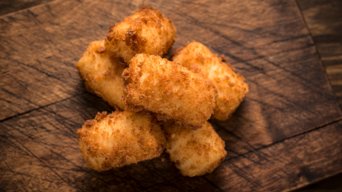 Croquetas doradas y crujientes servidas sobre una tabla de madera, imagen representativa del festival Croqueta Crush en Barcelona