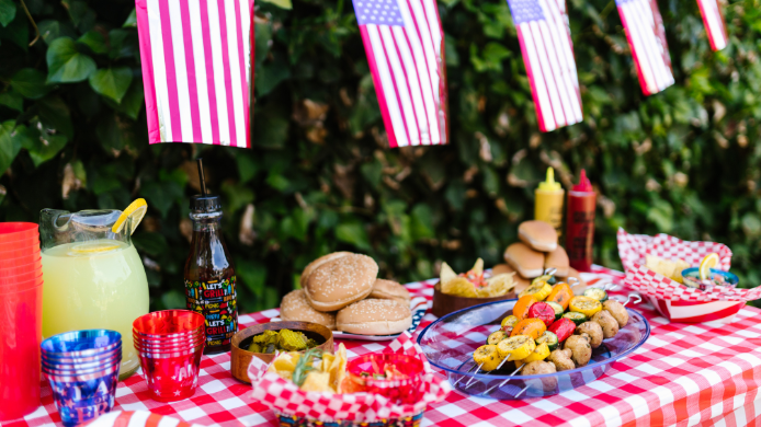 Mesa preparada para celebrar el Día de la Independencia de Estados Unidos con hamburguesas, brochetas, limonada y decoración con banderas estadounidenses, una de las imágenes más representativas de la gastronomía del 4 de julio