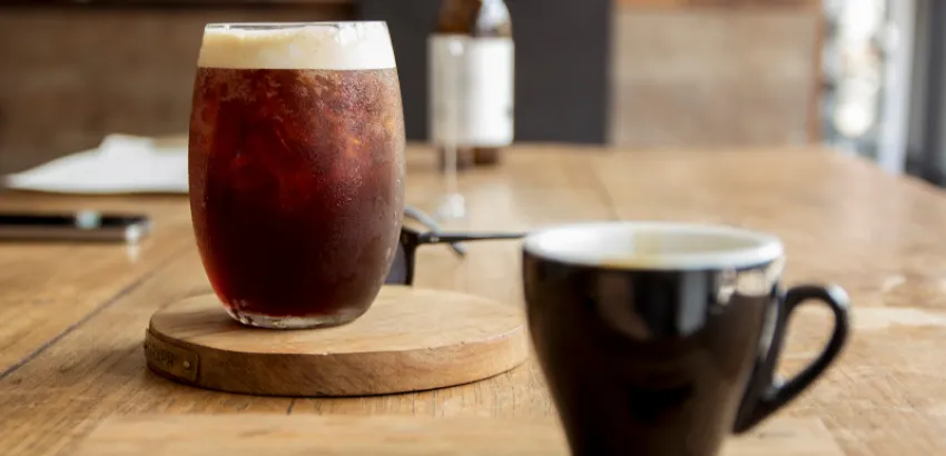 ¿Cómo prefieres el café frío o caliente? vaso de café con hielo y taza de café caliente