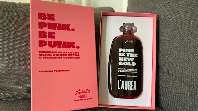 Botella de Aurelia, el aceite rosa de L’AUREA elaborado con AOVE Picual y pigmentos vegetales de remolacha, presentada en su estuche rosa.