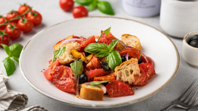 Ensalada panzanella italiana con tomate, pan tostado, cebolla morada, aceitunas y albahaca fresca