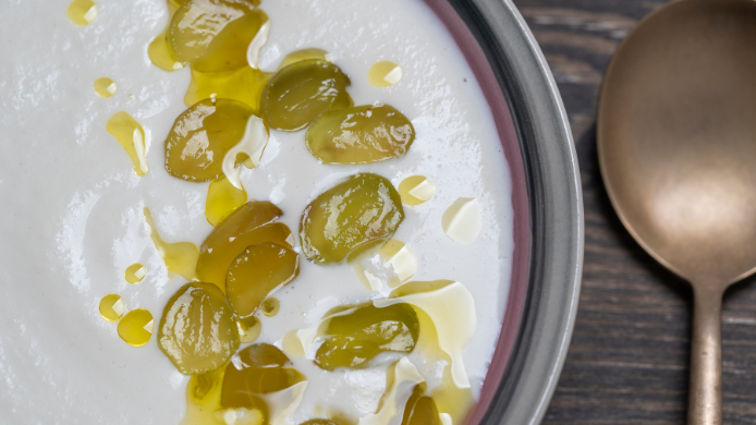 rema fría de ajoblanco con uvas y aceite de oliva en un plato hondo gris.