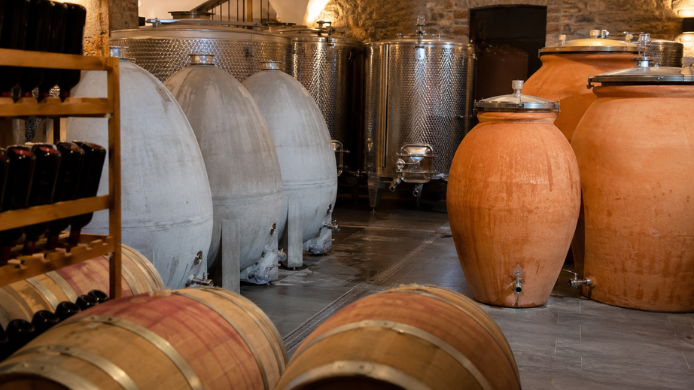 Interior de una bodega con barricas de roble, depósitos de acero inoxidable, huevos de cemento y ánforas de arcilla utilizados en la guarda y crianza del vino.