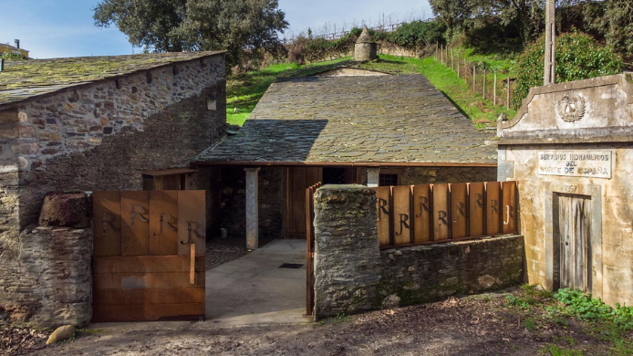 Exterior de la bodega Joaquín Rebolledo en Valdeorras, un conjunto tradicional de piedra integrado en el paisaje vitivinícola gallego y rodeado de viñedos de la D.O. Valdeorras.