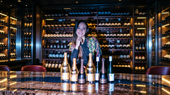 Dana Cárdenas, sumiller de Quinto Elemento y Sexto, posa ante una selección de vinos en la bodega de Teatro Kapital Madrid.