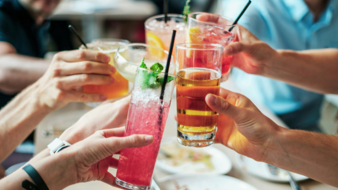 Grupo de personas brindando con bebidas alcohólicas  en la mesa de un restaurante.