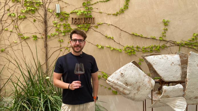 Sergio Otero en el jardín de Desde 1911, junto a una escultura de peces y una pared cubierta de enredaderas.