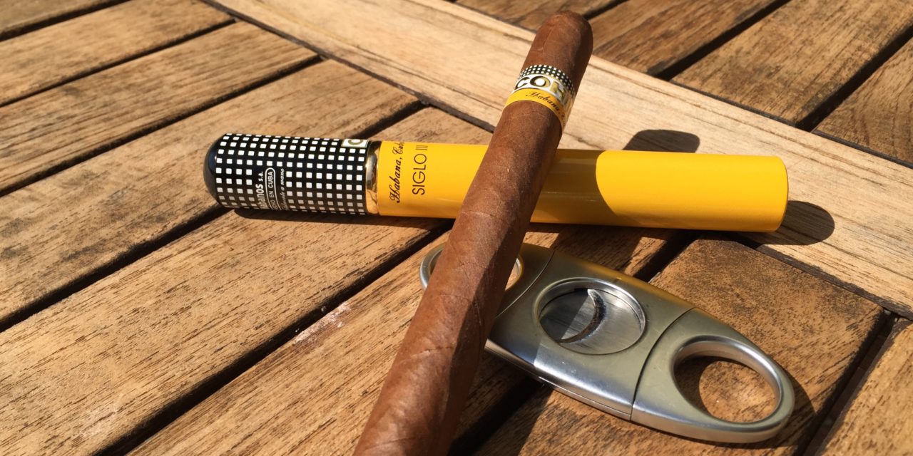 Habano Cohiba Siglo III con cortapuros sobre mesa de madera al sol