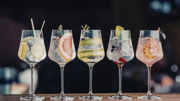 Copas de cócteles decoradas con cítricos, hierbas aromáticas y frutas, ejemplo de garnish contemporáneo en coctelería premium.