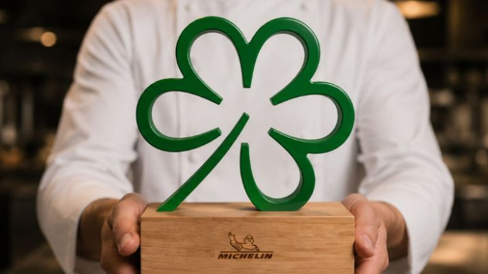 Chef sosteniendo el distintivo de la Estrella Verde de la Guía Michelin, reconocimiento vinculado a prácticas sostenibles en restauración y protagonista del cambio anunciado por la guía.