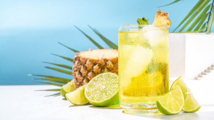 limonada de piña con hielo, decorado con una rodaja de piña y rodeado de limas frescas
