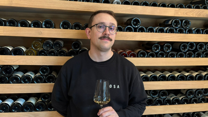 Alfredo Amat, sumiller del restaurante Osa de Madrid, posa con una copa de vino frente a la cava del restaurante.