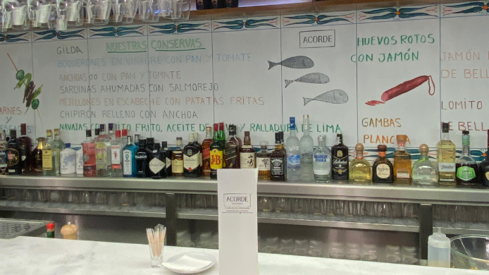 Barra de Cervecería Acorde en Madrid, con botellas, carta pintada en azulejos y ambiente de taberna junto al Movistar Arena.