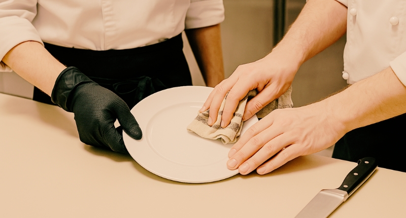 Cocina en equipo Dos manos colaborando en una cocina profesional, símbolo del trabajo en equipo y del valor del oficio gastronómico