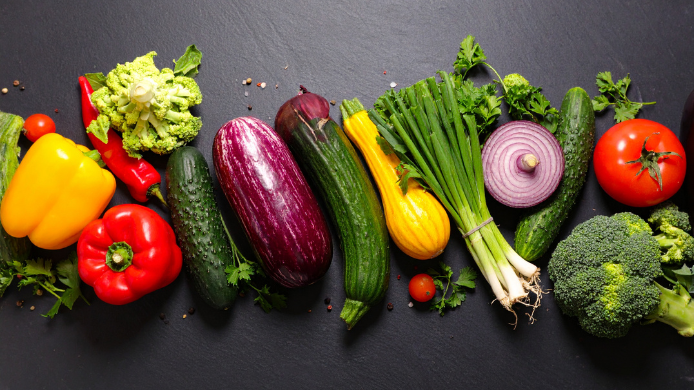 Verduras frescas variadas con pimientos, calabacín, berenjena, brócoli, cebolla y tomate sobre fondo oscuro, Alimentos vegetales saludables
