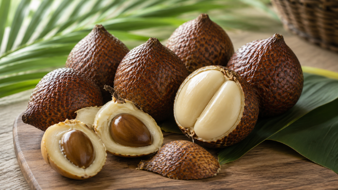 Frutos de salak de Indonesia con su característica piel marrón escamosa y varios ejemplares abiertos mostrando la pulpa clara y las semillas
