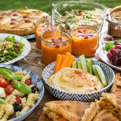 Mesa de verano al aire libre con salmorejo, ensalada de pasta, hummus, fruta fresca, empanada y recetas fáciles para compartir.